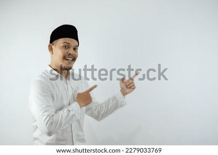 Asian muslim man pointing something on his side with his both hand over white background