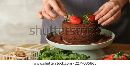 Female confectioner decorating tasty chocolate cake, closeup