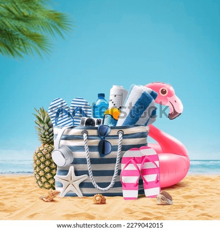 Beach bag with accessories and cute inflatable flamingo on a tropical beach, summer vacations and travel concept Royalty-Free Stock Photo #2279042015