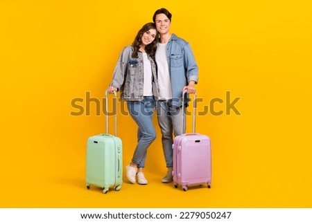 Photo of cute confident young couple dressed denim embracing going trip isolated yellow color background