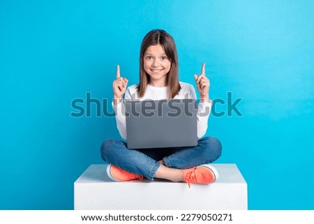 Full length photo of nice schoolgirl dressed white shirt jeans directing empty space sit with laptop isolated on blue color background Royalty-Free Stock Photo #2279050271