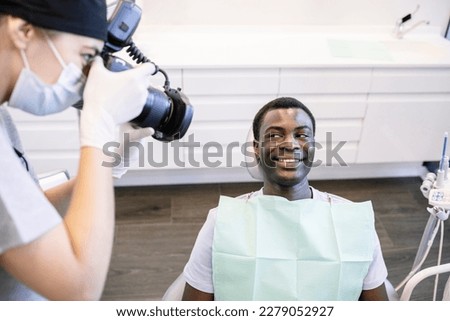 Dentist photographing patient's teeth through camera at medical clinic