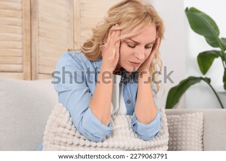 Woman suffering from headache on sofa at home. Hormonal disorders Royalty-Free Stock Photo #2279063791