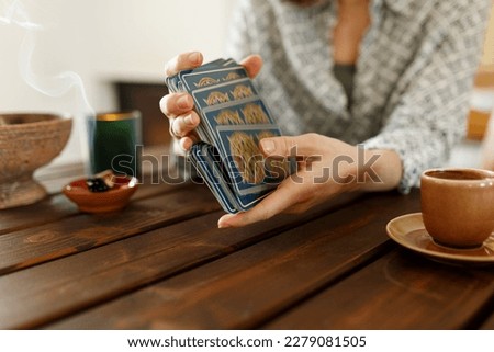 Fortune teller with tarot cards on table near burning candle.Tarot cards spread on table with magic herbs and palo santo aroma sticks. Forecasting concept Royalty-Free Stock Photo #2279081505