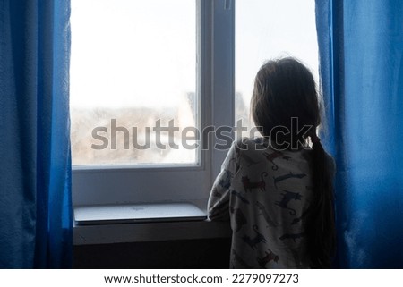 Kid's Depression. Unhappy Little Girl Sitting Feeling Lonely Near Window Hugging Herself At Home. Copy Space. Royalty-Free Stock Photo #2279097273