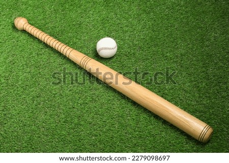Wooden baseball bat and ball on green grass, above view. Sports equipment