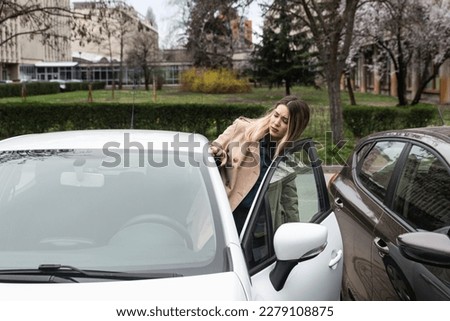 Young business woman having issue and hard time to enter the car on drivers door because of tight parking lot space and space between the cars Royalty-Free Stock Photo #2279108875