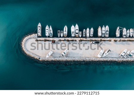 	 The composition of the image creates a beautiful abstract pattern that draws the viewer's eye to the different shades of blue and green water, as well as the boats lining the shoreline.	
