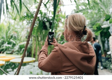 Caucasian middle age woman making photo of tropical botanical garden