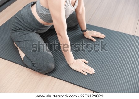 Picture of a beautiful girl practicing indoor yoga, calm and relaxed, preparation a yoga mat for her exercise.