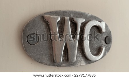 Metal WC Sign on a white wooden door .