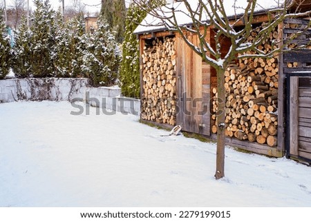 picture with wooden sheds for storing firewood in the yard. High quality photofirewood, prepared for the winter, lying under the canopy. Wood for the fireplace on a winter day. Snow and firewood 