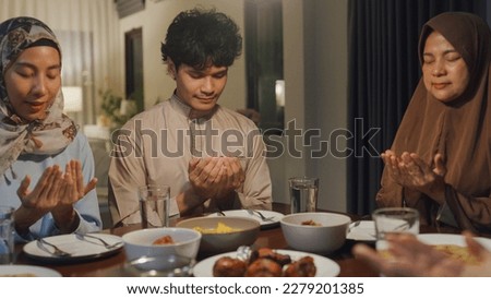 Happy Asian muslim family mother and child praying to god before eating Ramadan dinner together at home. Two generation celebration of Eid al-Fitr togetherness at home. Hari Raya family reunion. Royalty-Free Stock Photo #2279201385