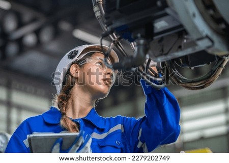 woman engineer in uniform helmet inspection check control heavy machine robot arm construction installation in industrial factory. technician worker check for repair maintenance electronic operation Royalty-Free Stock Photo #2279202749