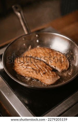 The process of cooking a duck breast, frying and baking in a pan, chef, male cook's hands, in dark tones, juicy close-up, fat fried butter, raw meat