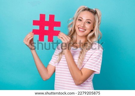 Photo of cheerful adorable lady toothy smile hands hold paper hashtag symbol isolated on teal color background