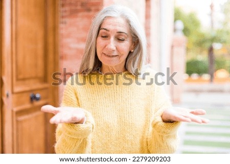 senior retired pretty white hair woman holding an object with both hands on copy space, showing, offering or advertising an object