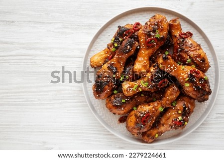 Homemade Easy Sticky Chicken Drumsticks on a Plate on a white wooden background, top view. Overhead, from above, flat lay. Copy space. Royalty-Free Stock Photo #2279224661