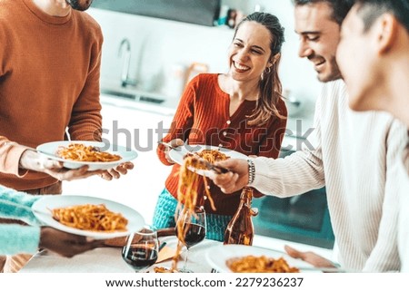 Happy group of friends eating pasta at home dinner party - Cheerful young people having lunch break together - Life style concept with guys and girls celebrating thanksgiving - Bright filter Royalty-Free Stock Photo #2279236237