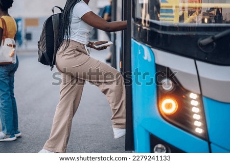 Cropped shot of an african american woman entering the bus while standing at the station.Black unrecognized female get in the public transportation while going to work or school. Copy space. Royalty-Free Stock Photo #2279241133