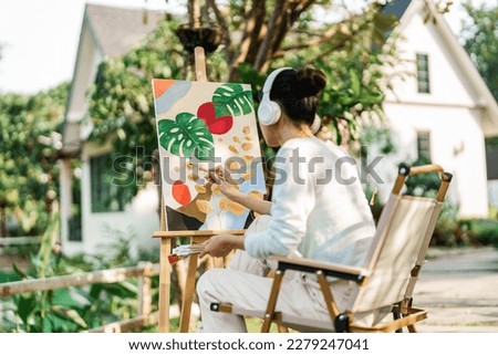 Young asian woman artist painting on canvas.
Female artist drawing with inspiration in garden