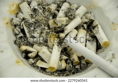 Close up view of dirt ashtray full of burnt cigarettes. Choose life.
