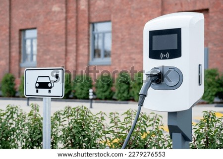 e-car charging station, e-car charge point or electric vehicle supply equipment (EVSE) with information sign electric car public charging point station and charge cable, charging plug parking spaces Royalty-Free Stock Photo #2279276553