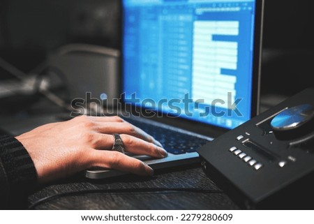 Male hand with long nails mixing song at daw on laptop, mixing engineer in recording studio