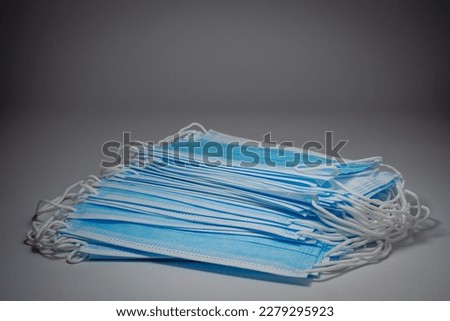 Blue surgical masks stacked in layers on middle gray background, Bacteria protection concept.