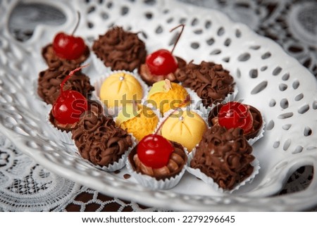 Oval plate with manna sweets, cherries and truffles.