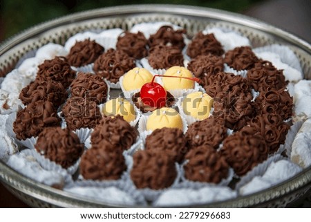 Circular plate with manna sweets, cherries and truffles.