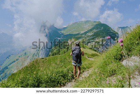 Asian women hiking in the Swiss Alps mountains during summer vacation with a backpack and hiking boots. woman walking on the Saxer Lucke path a popular hiking trail in Switzerland Royalty-Free Stock Photo #2279297571