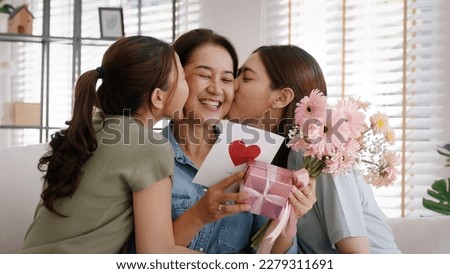 Mother day two grown up child cuddle hug give flower gift box red heart card to mature mum. Love kiss care mom asia middle age adult three people sitting at home sofa happy smile enjoy family time. Royalty-Free Stock Photo #2279311691