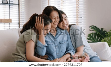 Happy time May Mother day cuddle hug care love face to face kiss cheek to mature mum. Asia middle aged old mom adult people smile enjoy receive gift flower from young child sitting at home sofa relax. Royalty-Free Stock Photo #2279311707
