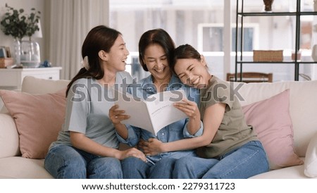 Buy mediclaim health care life insure for older mum. Young adult woman asia people grown up child give gift to middle aged mom reading protect cover saving plan paper smile laugh sitting at sofa home. Royalty-Free Stock Photo #2279311723