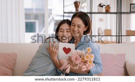 May Mother's day young adult grown up child cuddle hug give flower gift box red heart card to mature middle aged mum. Love kiss care mom asia people sitting at home sofa happy smile enjoy family time. Royalty-Free Stock Photo #2279311811
