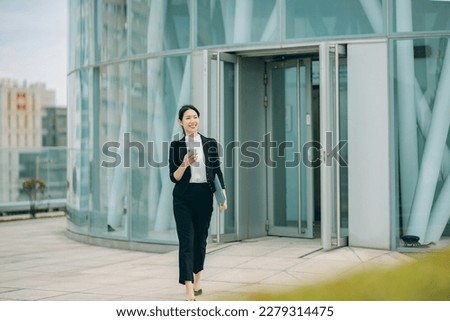 Successful Asian Chinese businesswoman using smart phone on city street, 