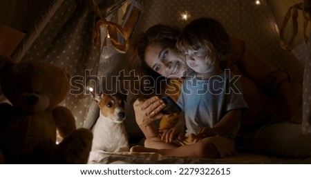 Tablet, night a mother reading to her child in a tent while camping in the bedroom of their home together. Caucasian family, story for kids with a woman storytelling to her kid at bedtime for bonding