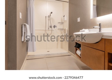 Wheelchair accessible hotel bathroom shower with tile floor and walls. Royalty-Free Stock Photo #2279346477