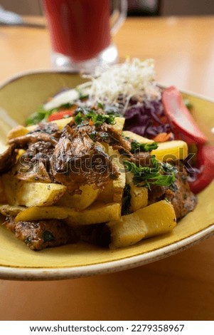 A vegan twist on the classic Peruvian dish "Lomo Saltado": made with stir-fried mushrooms, onions, tomatoes, and sweet potato fries, seasoned with soy sauce and aji amarillo peppers Royalty-Free Stock Photo #2279358967