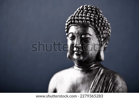 Meditating Buddha Statue on dark background. Close up. Copy space.                                