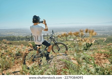 Cycling, fitness and man on a bicycle with phone for picture, photography or photo in nature. Cyclist, workout and social media health influencer live streaming for blog, website or profile picture