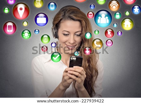 communication technology mobile high tech concept. Young woman using texting listening to music on smartphone with social media application symbols icons flying out of screen isolated grey background.