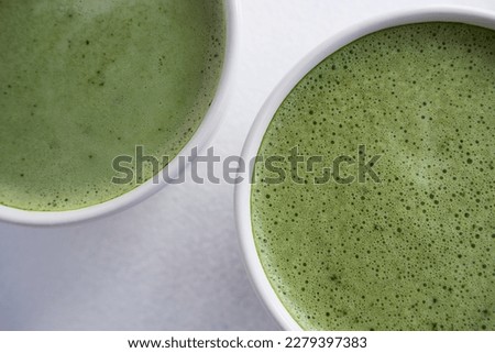 Green tea in a white mug on a white background, photo from above. Matcha foamed, dietary and healthy drink.