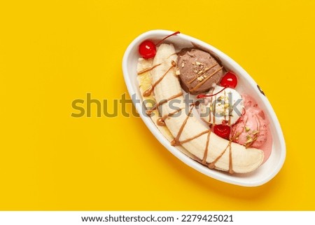 Delicious sweet banana split ice cream dessert with caramel syrup or topping and cherry. Top view. Copy space Royalty-Free Stock Photo #2279425021