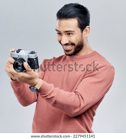Camera, photography and happy with asian man in studio for photoshoot, satisfaction and creative. Vintage, photographer and production with male on white background for shooting, lens and hobby