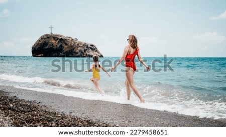Happy loving family mother and daughter having fun together on the beach. Mum playing with her kid in holiday vacation next to the ocean - Family lifestyle and love concept
