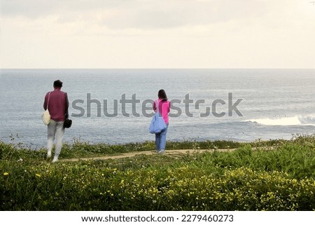 Young couple taking pictures at the ocean on a cloudy day