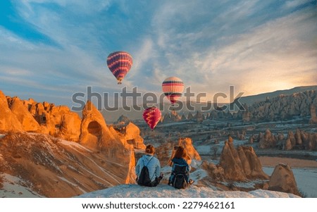 Hot air balloon flying over spectacular Cappadocia - Girls watching hot air balloon at the hill of Cappadocia Royalty-Free Stock Photo #2279462161