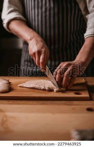 the male chef makes incisions on the skin of the duck breast meat, a knife in the hands of a professional cook, raw, copy space, manufacturing